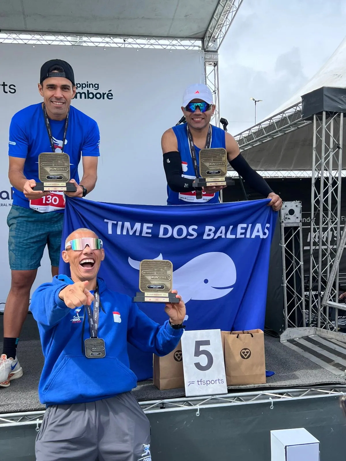 Três atletas da Oseias Santos Run no pódio da Run Series com os troféus