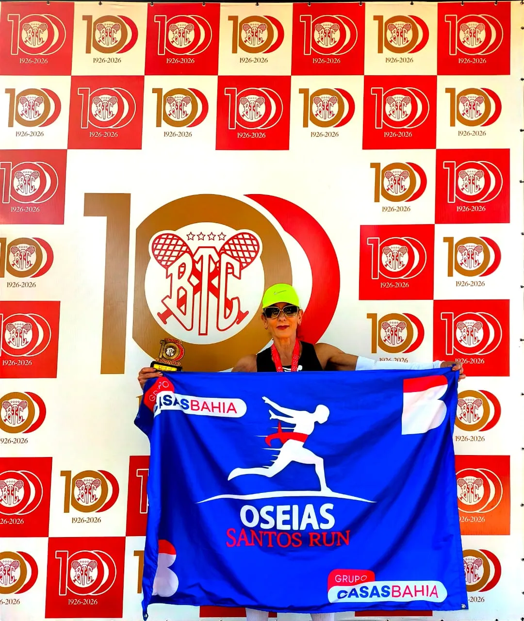 Atleta da Oseias Santos Run com o troféu do centenário do BTC e a bandeira da equipe